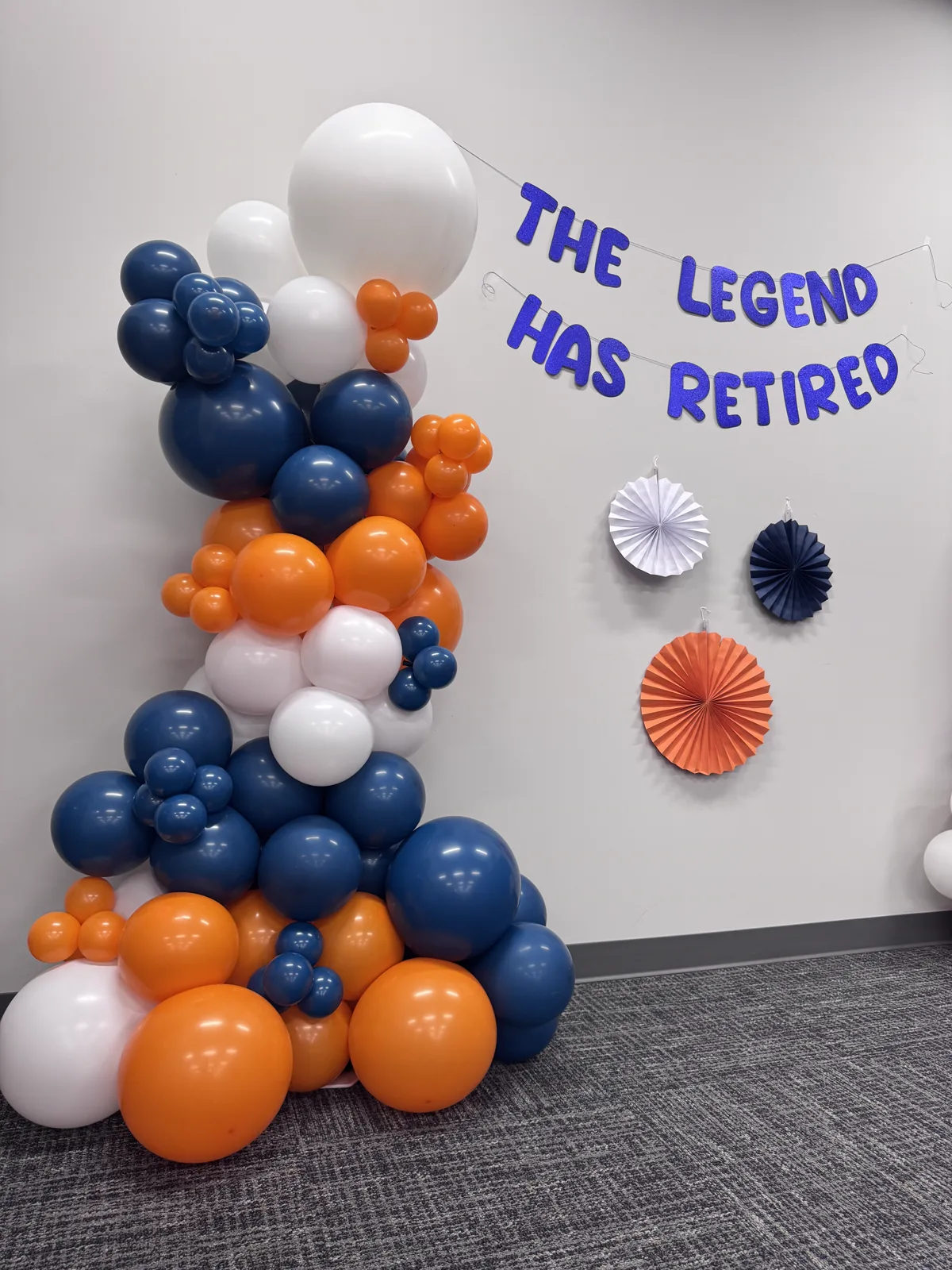 Navy, orange and white balloon garland for a retirement party with The Legend Has Retired banner